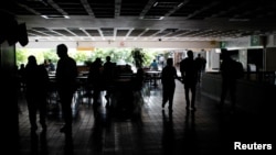 Personas se aglomeran en la oscuridad, en un centro comercial, en medio del apagón que afectó este jueves a gran parte de Venezuela.