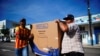Dos residentes de La Habana cargan un refrigerador adquirido en una tienda recuadadora de divisas. (REUTERS/Alexandre Meneghini).