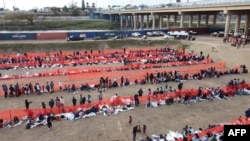 (ARCHIVO) Los inmigrantes esperan ser procesados en un centro de tránsito de la Patrulla Fronteriza de EEUU después de cruzar la frontera desde México en Eagle Pass, Texas, el 20 de diciembre de 2023. Francois PICARD / AFP.