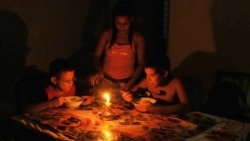 Noticias de Cuba en 5 minutos | 09/18/2024 Niños comen a la luz de una vela durante un apagón en Cuba en el año 2009. AFP PHOTO/STR / AFP PHOTO / STR