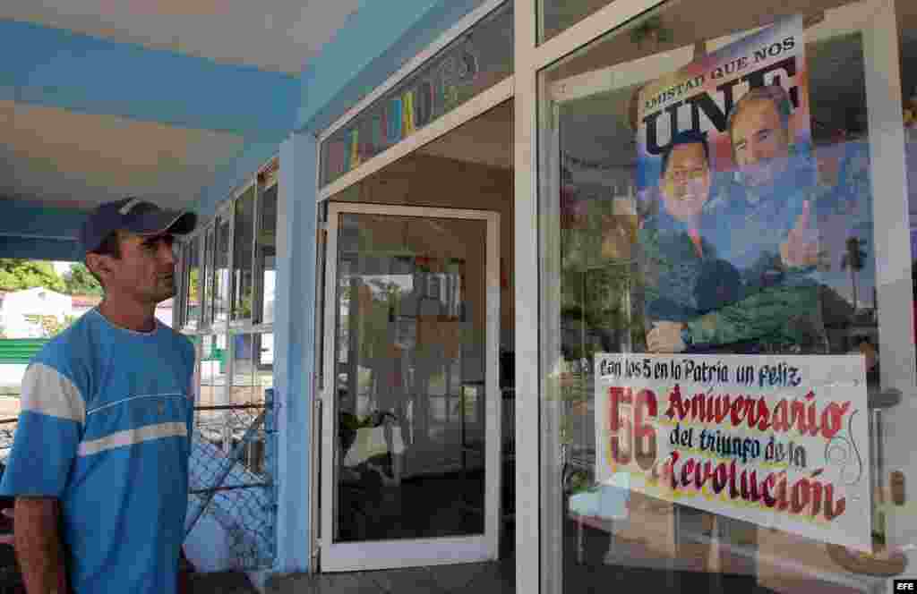 Un hombre observa un cartel con la imagen del líder cubano Fidel Castro y el fallecido presidente venezolano Hugo Chávez, junto a otro alusivo al nuevo aniversario de la Revolución cubana,el 31 de diciembre del 2014.