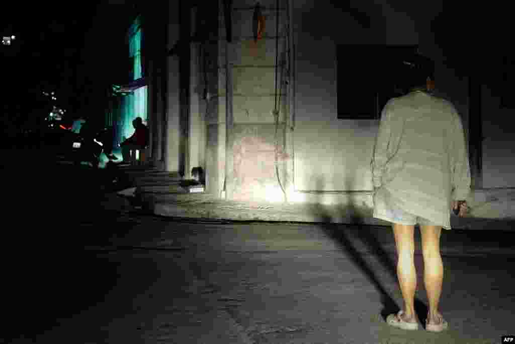 Una mujer está parada en una calle iluminada por las luces de un automóvil durante un apagón nacional el 4 de diciembre de 2024.