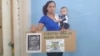 Nelva Ismarays Ortega, con su bebé en brazos y un cartel exigiendo la libertad de su esposo. (Katherine Mojena/CubaNet)