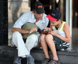 Padre e hijo navegan por la internet en un dispositivo móvil La Habana.