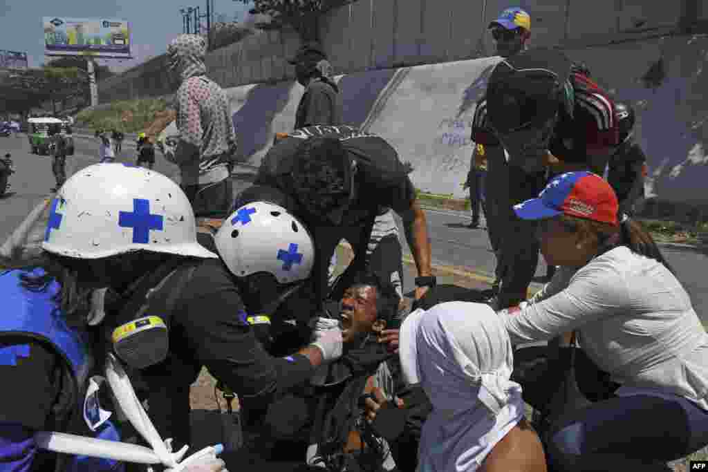 Un manifestante afectado por gas lacrimógeno es asistido durante un enfrentamiento con soldados bolivarianos en Caracas.
