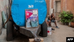 Un cubano descansa junto a un camión cisterna "pipa" donde han colocado un cartel con las figuras de Fidel y Raúl Castro el 9 de abril de 2018.