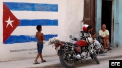 Un niño pasa junto a una pintura de la bandera cubana en una pared, en La Habana, Cuba.