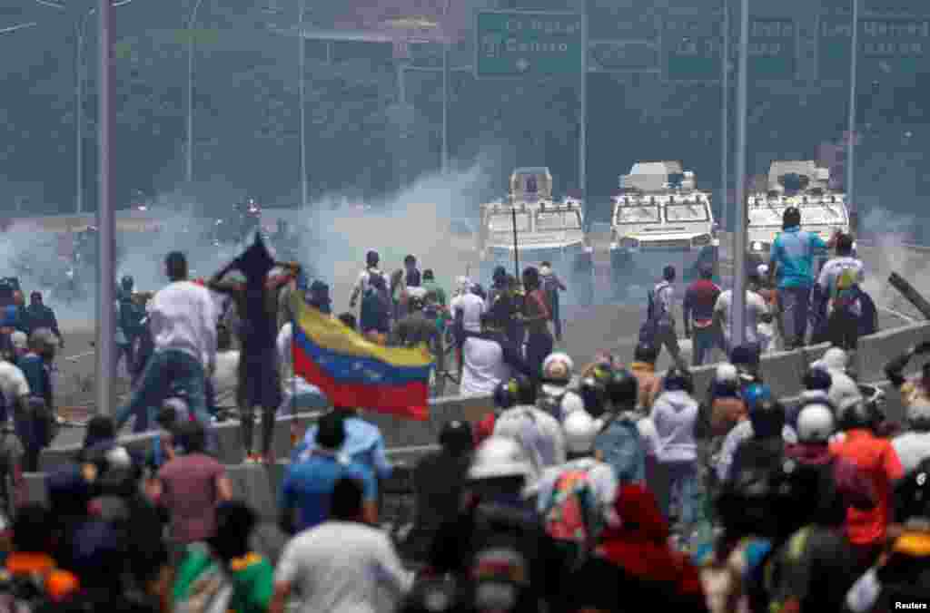 Manifestantes enfrentan los vehículos militares, cerca de la base La Carlota, en Caracas.