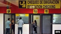 Dos mujeres chequean su pasaportes en las cabinas de emigración del aeropuerto Internacional José Martí hoy, martes 16 de octubre de 2012, en La Habana (Cuba). Cuba anunció hoy la eliminación de los permisos de salida para viajar al extranjero y dejará s