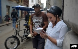 Una mujer se conecta a internet desde su celular en una calle de La Habana.