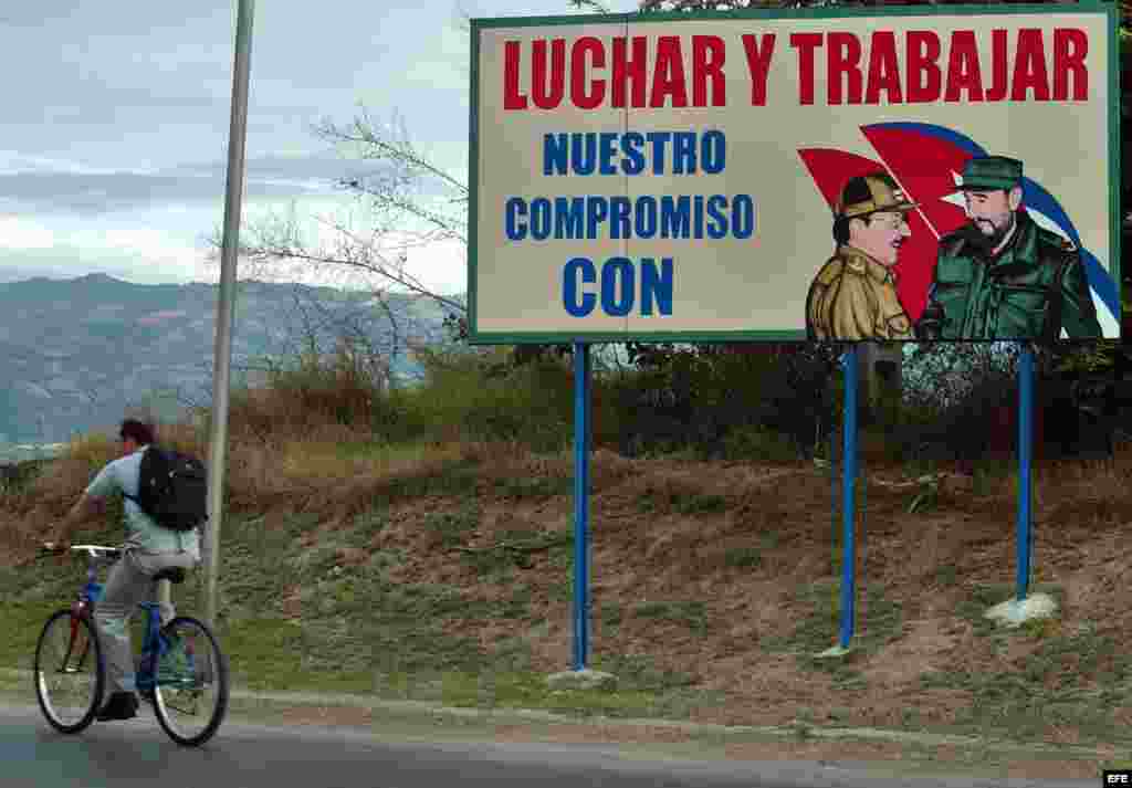 Un hombre pasa en bicicleta junto a un cartel con la foto de Fidel Castro en la provincia de Guantánamo, Cuba.